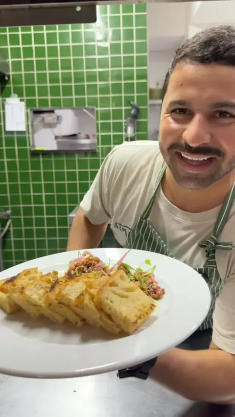 Alan Marcos sorrindo com um prato na mão