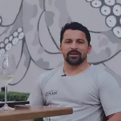 Chef Alan Marcos sentado em frente ao mural de polvo